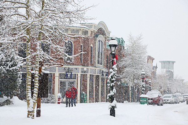A couple takes a stroll on a very snowy day in front of the Victorian storefronts of Main Street, Breckenridge.